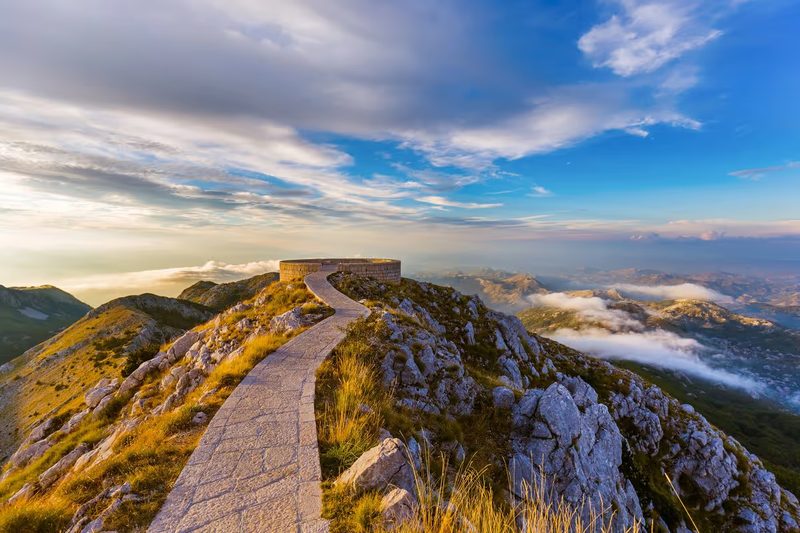 Sentier pavé menant au mausolée de Njegoš au sommet du mont Lovćen, vue panoramique sur les montagnes du Monténégro au lever du soleil