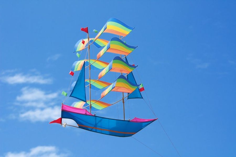 Cerf-volant coloré en forme de bateau naviguant dans le ciel bleu lors du Bali Kite Festival.