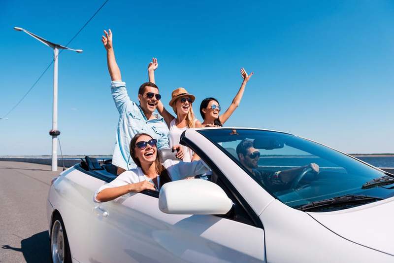 Groupe d'amis souriants en cabriolet blanc lors d'un road trip en voiture