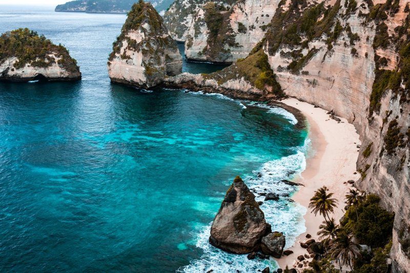 Une magnifique plage entourée de falaises, avec des eaux turquoise et des rochers imposants.