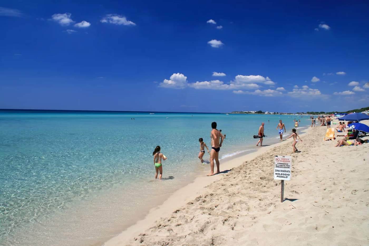 Plage de Punta Prosciutto avec des baigneurs profitant des eaux cristallines et du sable fin.