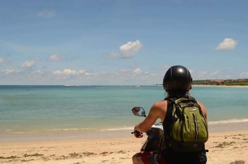 Une femme en scooter sur une plage de Bali