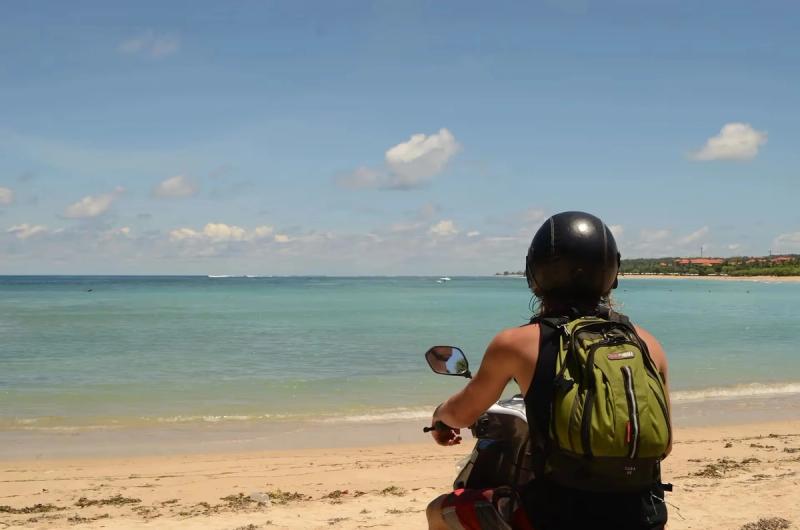 Une femme en scooter sur une plage de Bali