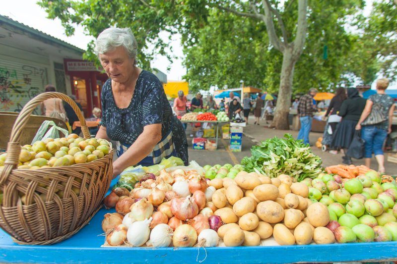 Une femme âgée disposant des fruits et légumes frais sur un marché animé à Split.