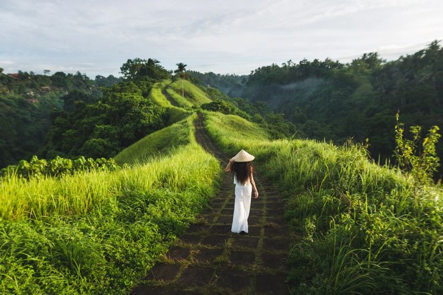 Voyageuse en robe blanche et chapeau conique sur le Campuhan Ridge Walk, Ubud