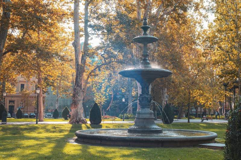 Fontaine historique dans le parc Zrinjevac, entourée d’arbres dorés en automne.