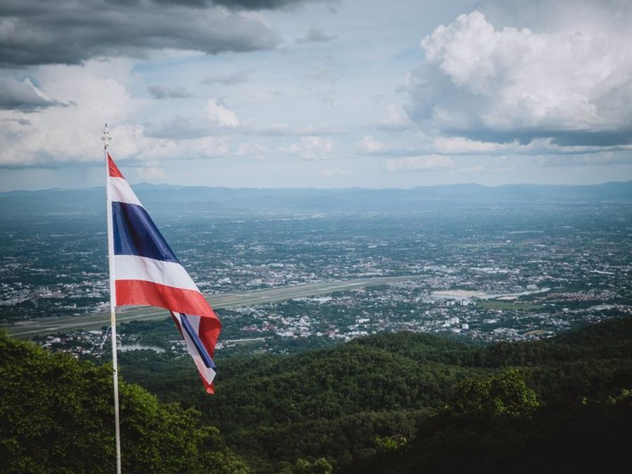 Vue panoramique de Doi Suthep avec un drapeau thaïlandais au premier plan.