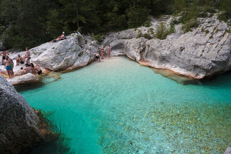 Baigneurs dans le bassin naturel de la Lépéna aux eaux turquoise, vallée de la Soča, Bovec, Slovénie