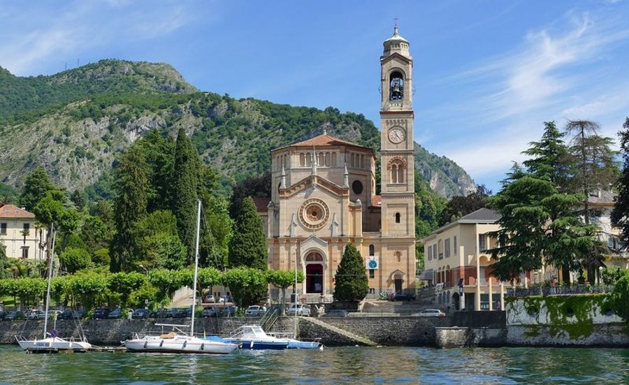 Église au bord du lac de Côme avec des montagnes en arrière-plan.