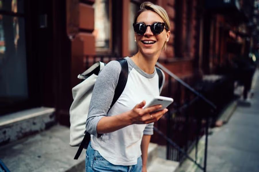 Femme souriante à Brooklyn tenant un téléphone dans sa main connecté avec une esim