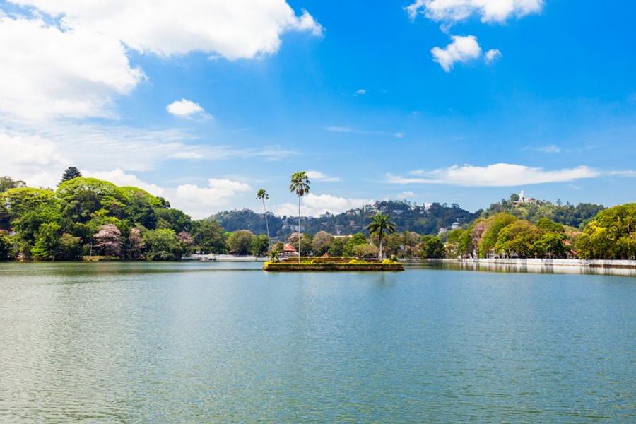 Vue sur le lac artificiel de Kandy, entouré de verdure et de montagnes en arrière-plan.