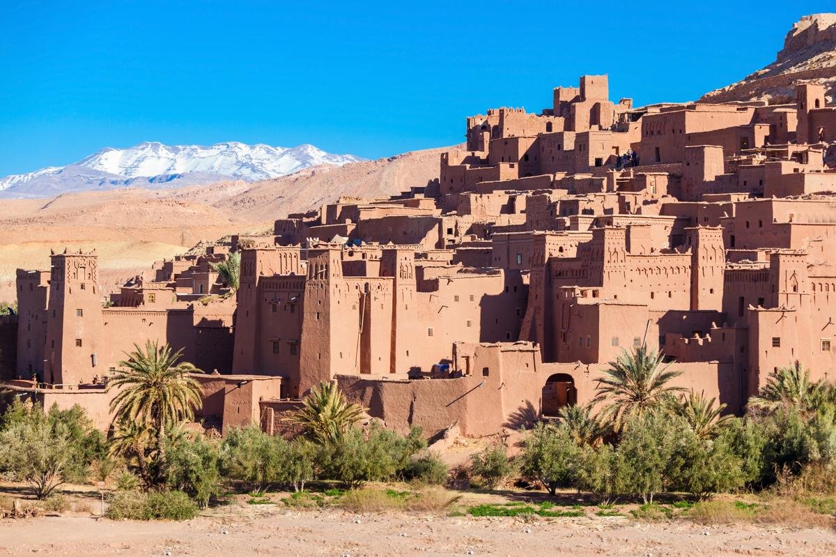 Vue sur le ksar d’Aït Ben Haddou avec les montagnes de l’Atlas enneigées en arrière-plan.