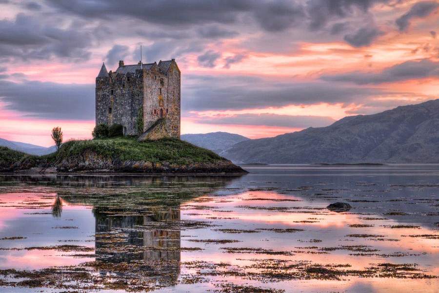 Château écossais posé sur une île dans un loch au coucher du soleil, dans les Highlands d’Écosse