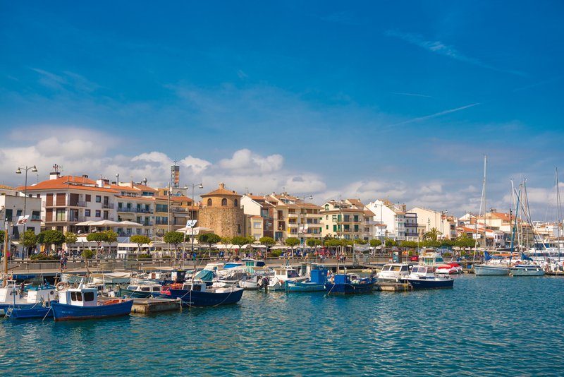 Le port de Cambrils avec ses bateaux amarrés sous un ciel bleu.