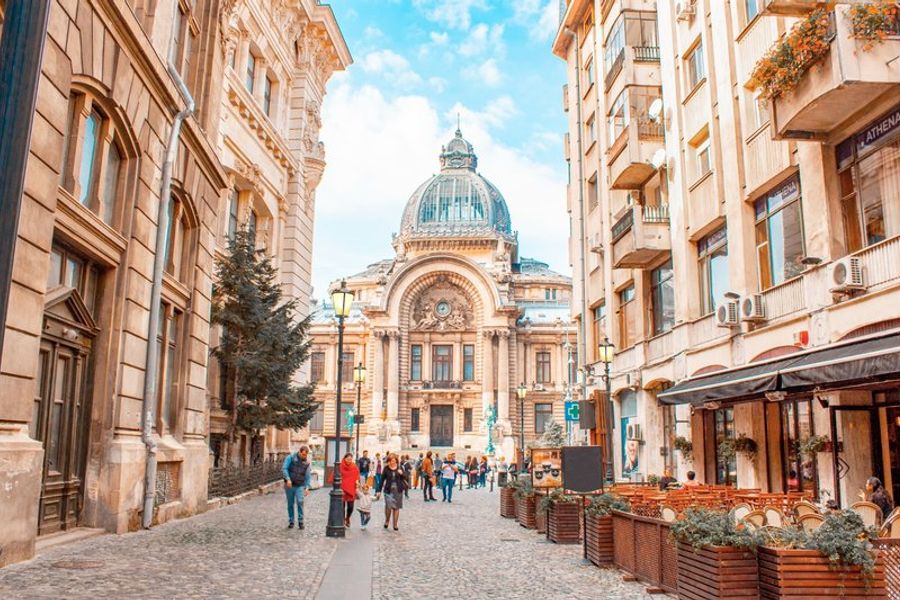 Rue animée et pavée du centre historique de Bucarest, bordée de bâtiments anciens et de cafés