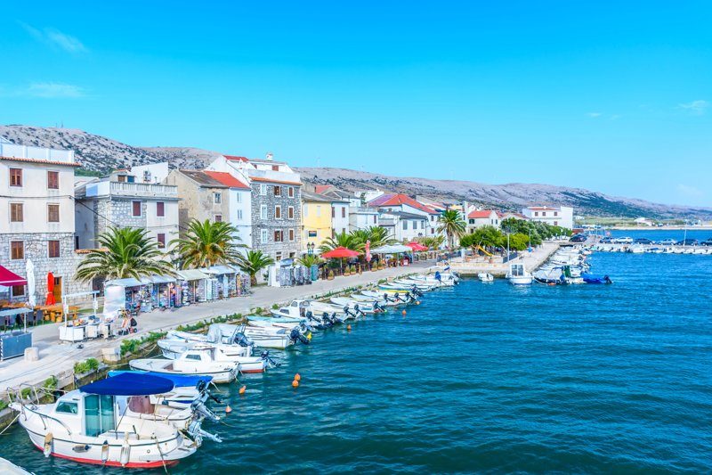 Le bord de mer de la ville de Pag avec ses bateaux amarrés et ses bâtiments colorés.