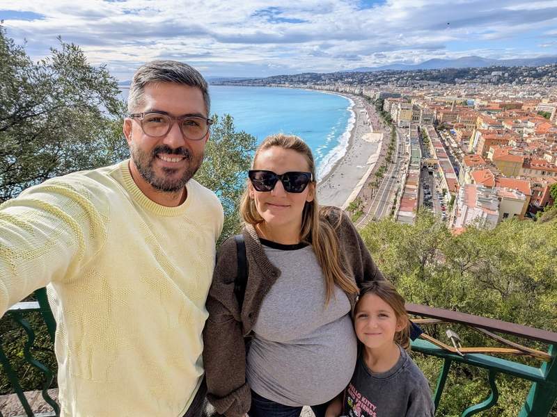 Famille posant devant la baie de Nice avec vue sur la Promenade des Anglais et la mer Méditerranée.