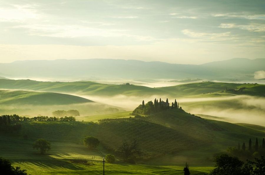 Paysage brumeux de la Toscane avec collines verdoyantes.