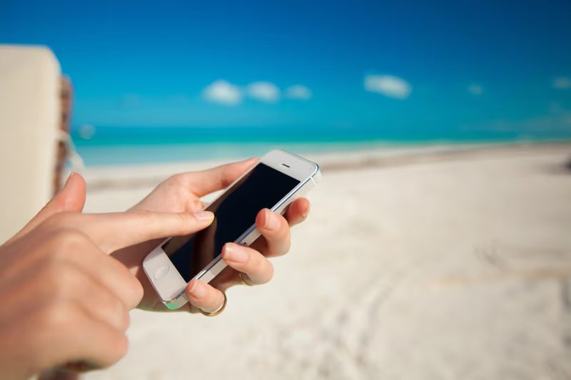 Touriste utilisant son smartphone sur une plage de sable blanc au Mexique grâce à une eSIM