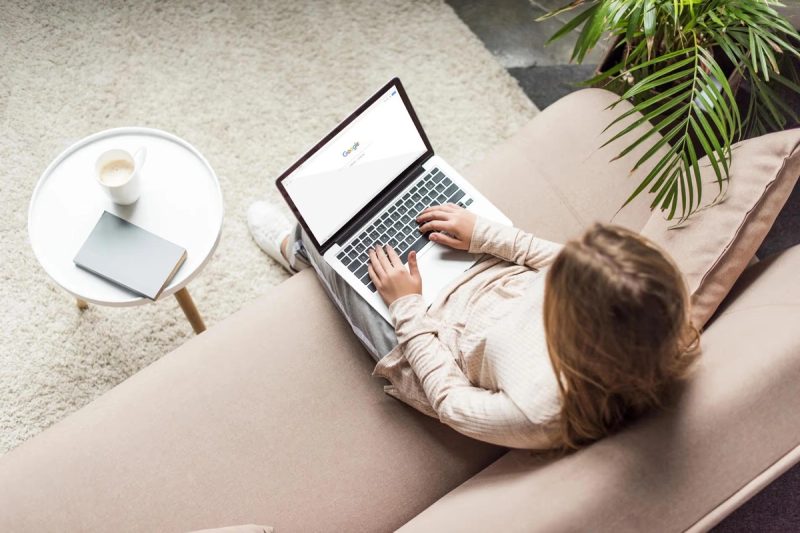 Personne travaillant sur un ordinateur portable avec Google sur l'écran, dans un cadre relaxant à la maison.