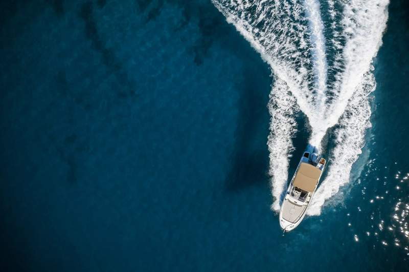 Vue aérienne d'un bateau de croisière naviguant sur une mer bleue avec un sillage en forme de V