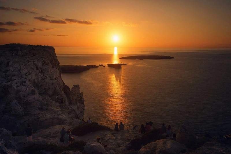 Magnifique coucher de soleil sur la mer en Espagne, vu depuis des falaises rocheuses avec des silhouettes de voyageurs admirant le paysage.