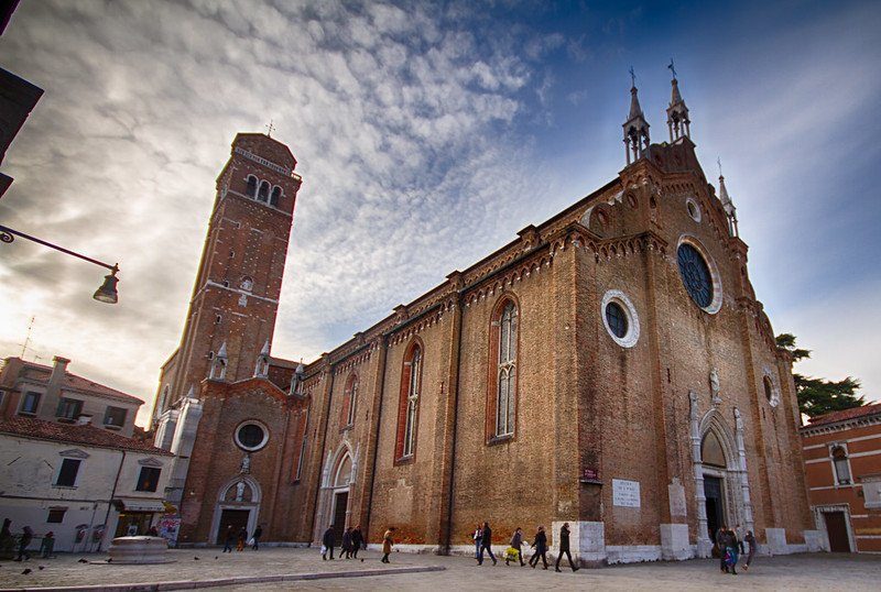 Vue de la basilique Santa Maria Gloriosa dei Frari avec son campanile sous un ciel partiellement nuageux.