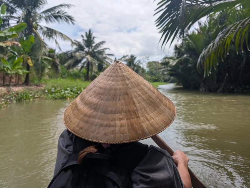 Maud avec chapeau traditionnel voguant en barque sur un canal à Ben Tre Vietnam