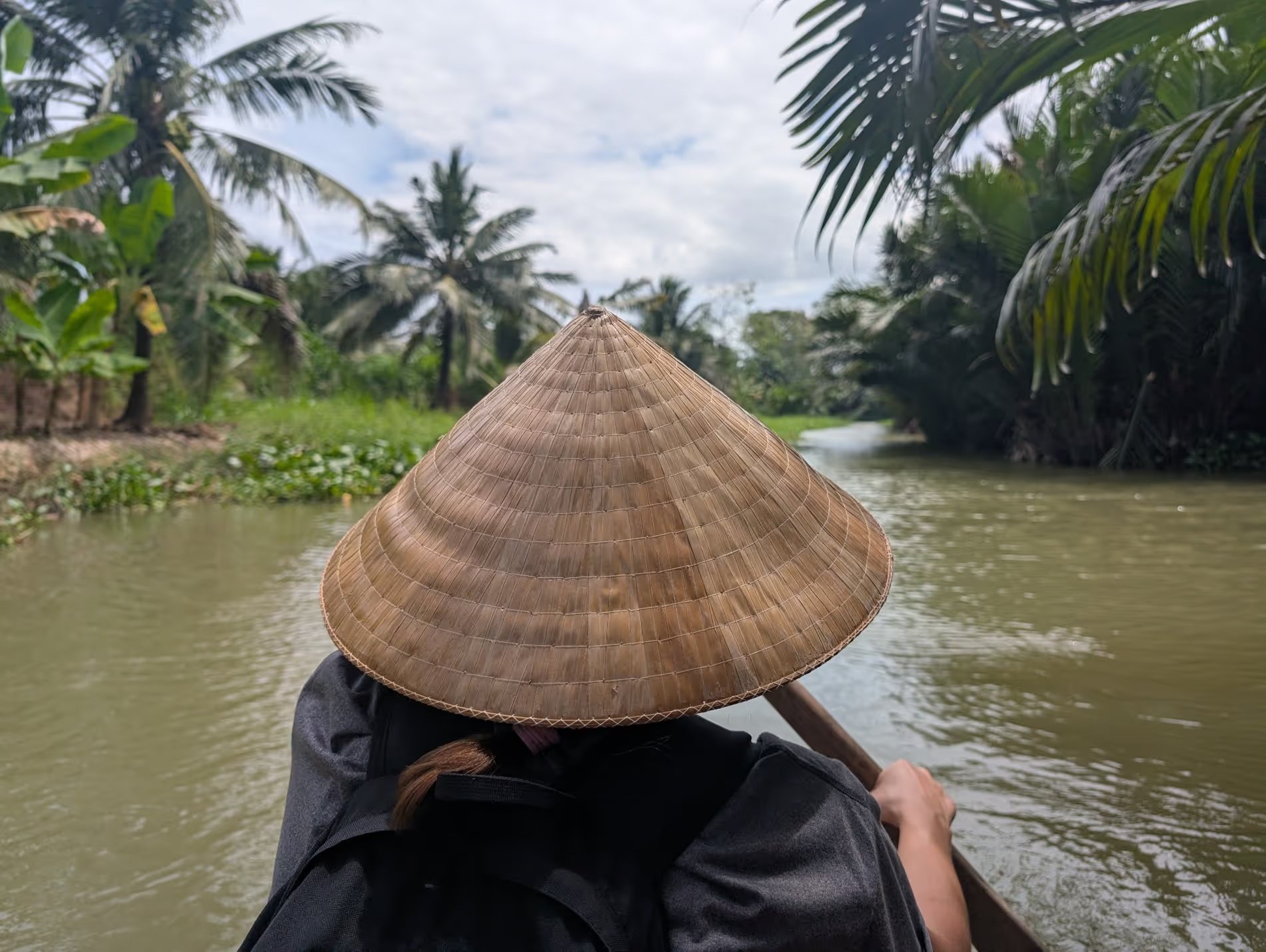 Maud avec chapeau traditionnel voguant en barque sur un canal à Ben Tre Vietnam
