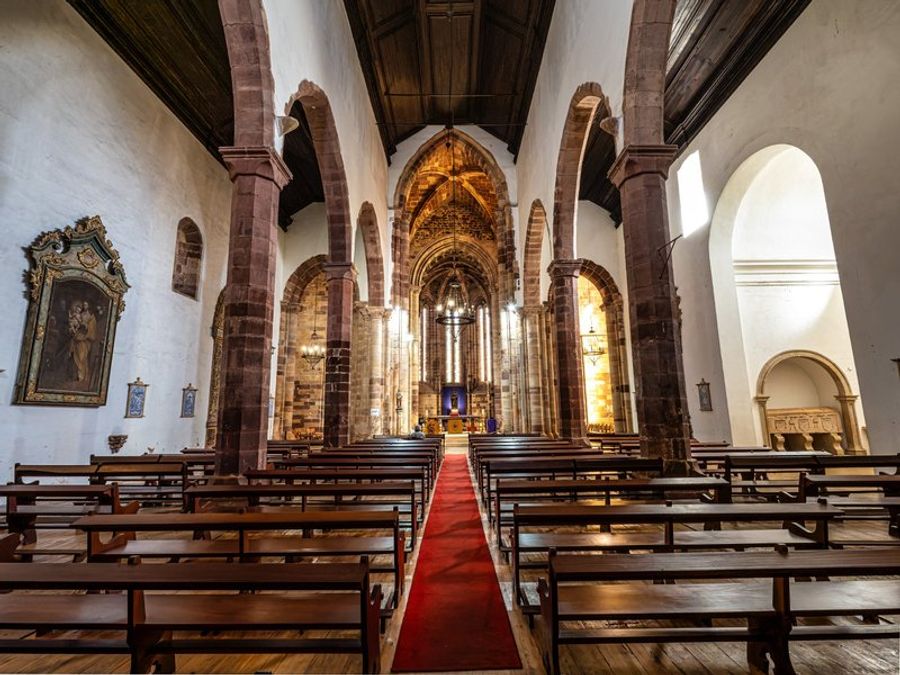 Intérieur majestueux de la cathédrale gothique de Silves, avec ses arcs en grès rouge et son allée centrale éclairée.