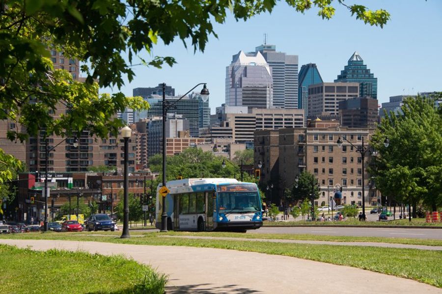 Bus en circulation dans le centre-ville de Montréal, entouré de gratte-ciels et d