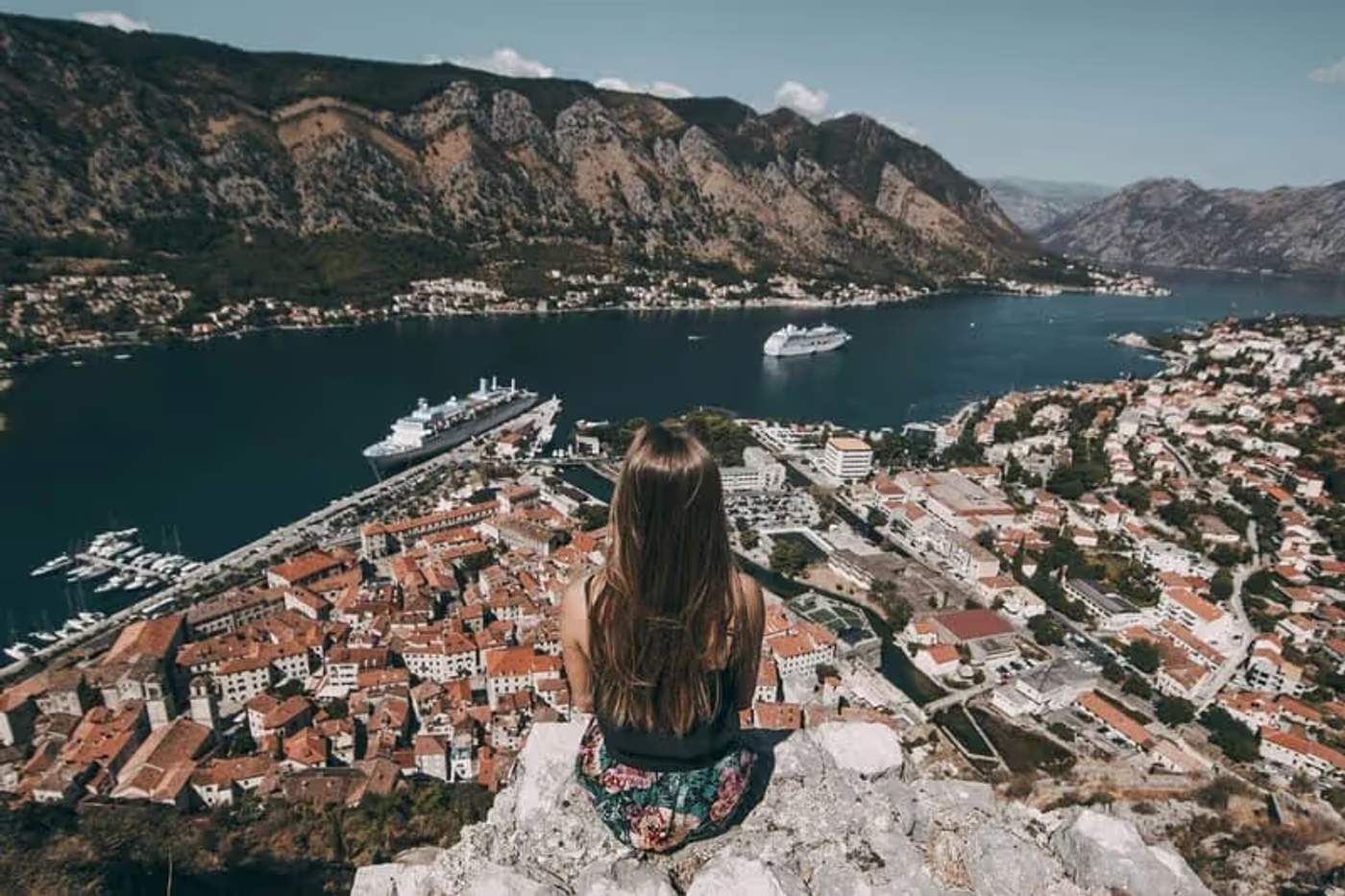 Une femme sui regarde la ville de Kotor au Monténégro depuis une falaise
