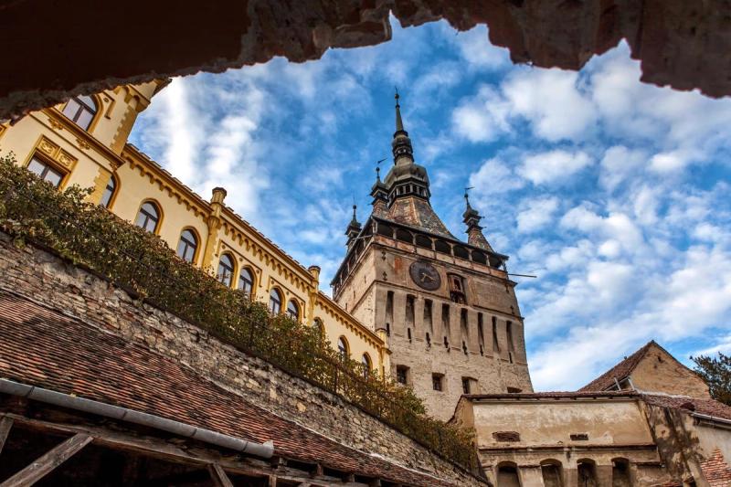 Vue pittoresque de la Tour de l'Horloge à Sighisoara, Roumanie, entourée d'architecture médiévale et d'un ciel bleu éclatant.