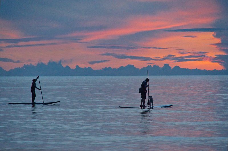 Deux personnes pratiquant le stand-up paddle au coucher du soleil sur la Costa Brava.
