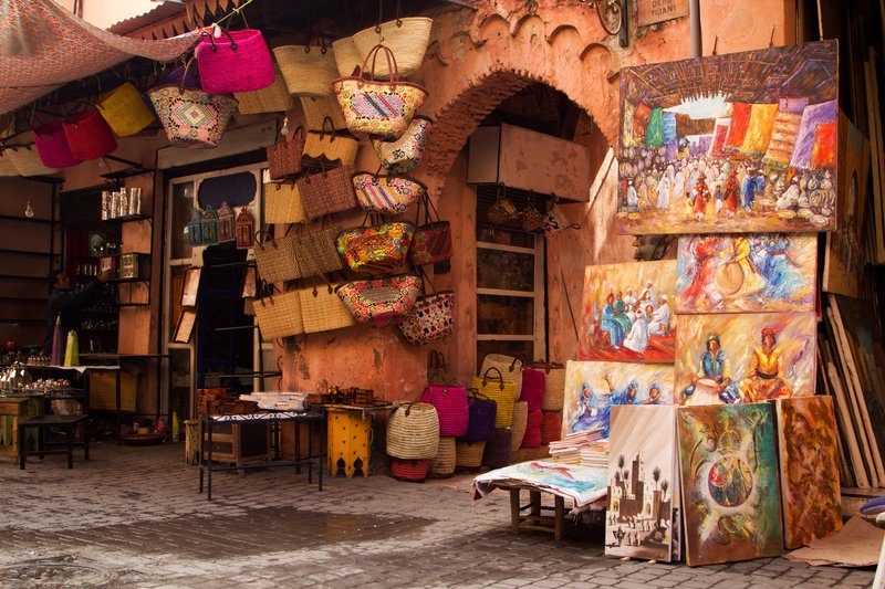 Scène typique dans la médina de Marrakech, entre paniers artisanaux, peintures locales et architecture ocre.