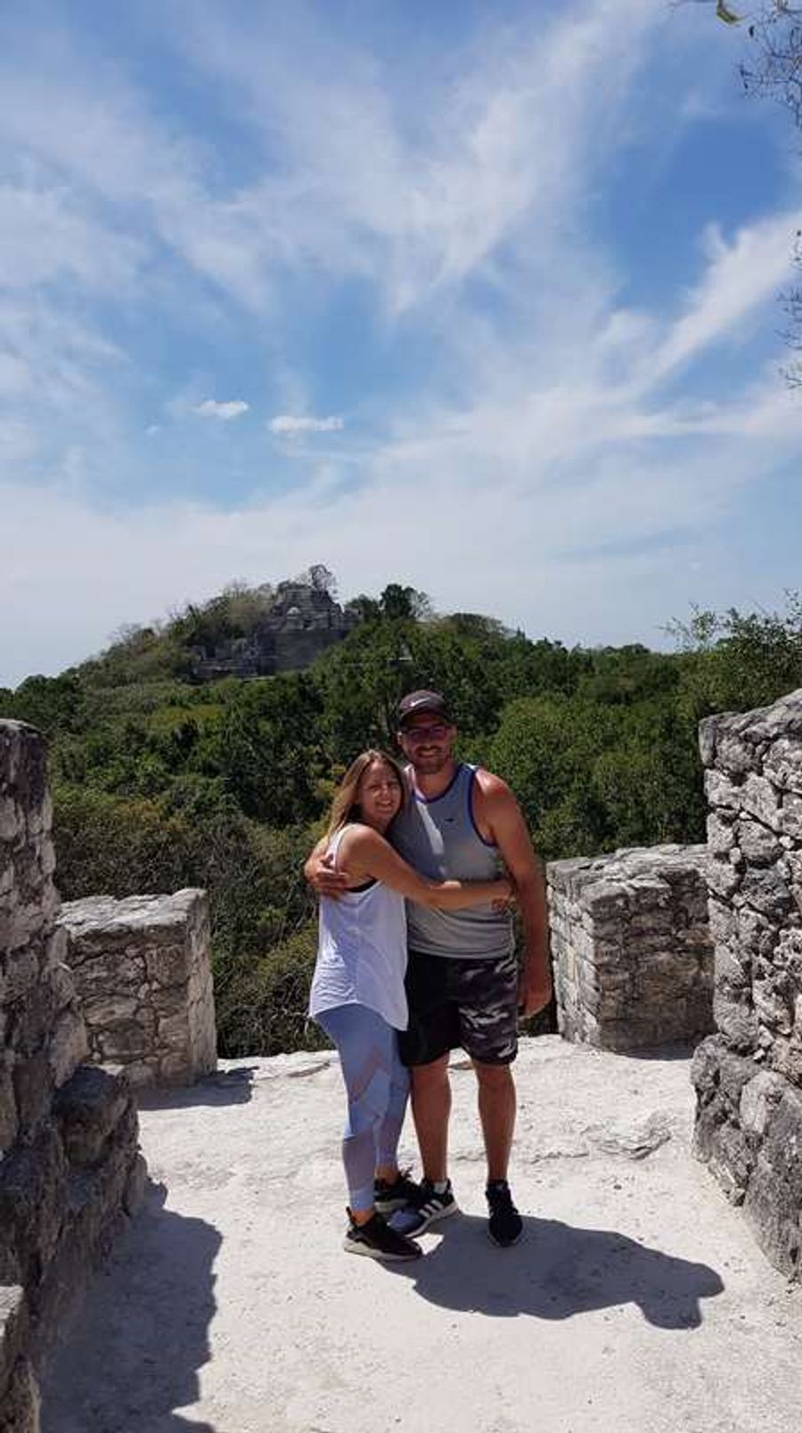 Un couple de voyageurs se tient devant les ruines d'un temple maya à Calakmul, photo en format portrait au cœur de la jungle