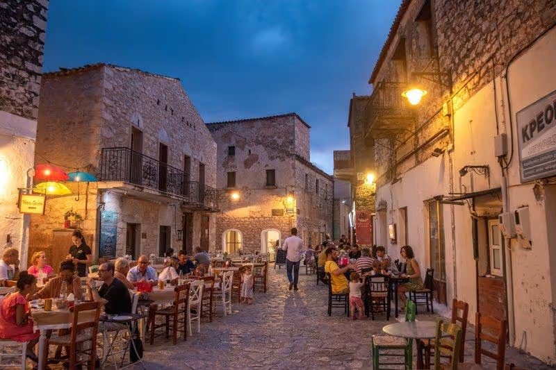 Rue animée d'Areopoli avec des restaurants en plein air et des bâtiments en pierre