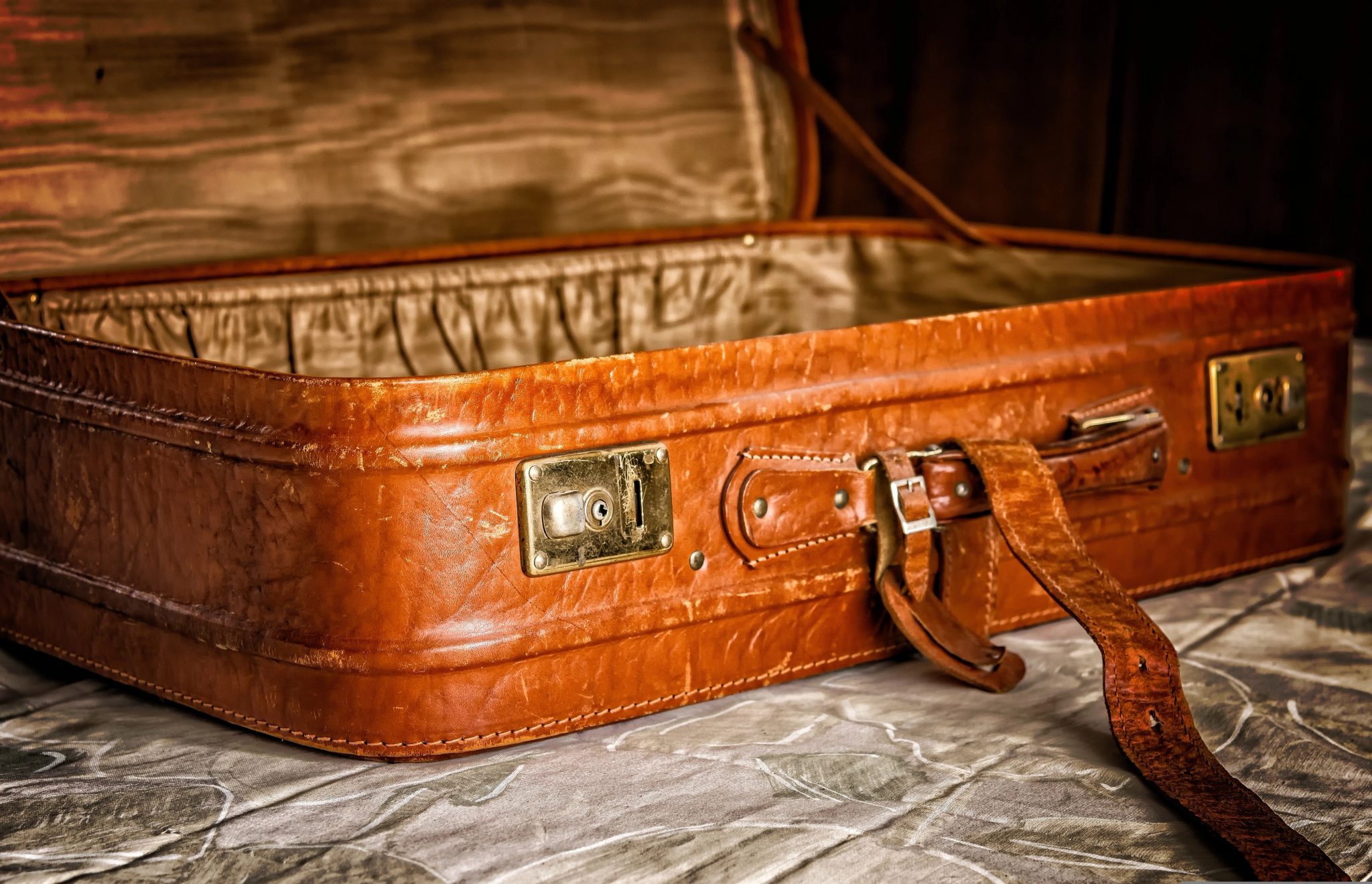 Valise en cuir ouverte posée sur un lit avant la préparation d’un voyage