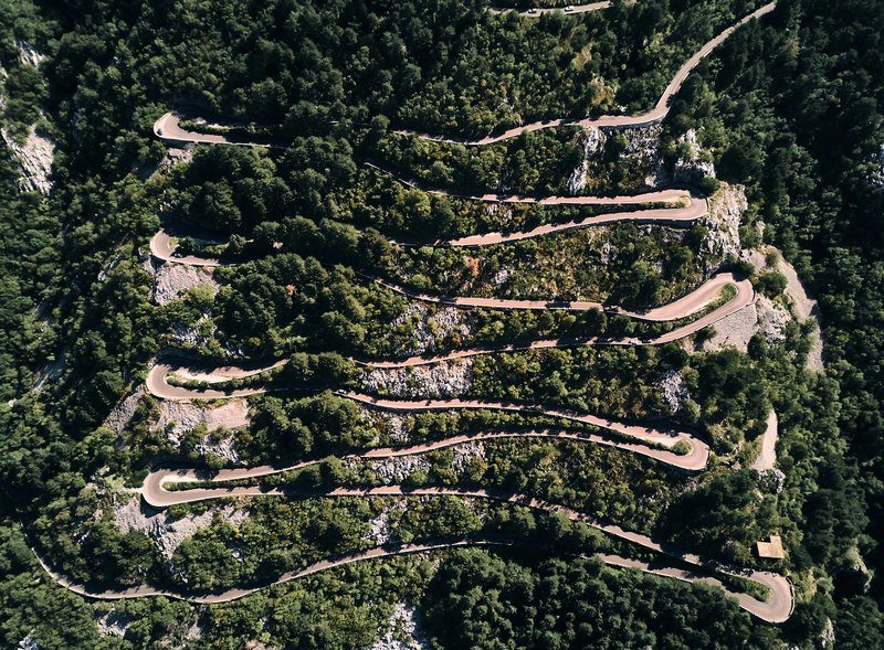 Vue aérienne de la route en lacets du mont Lovćen au Monténégro, avec ses nombreux virages en épingle à cheveux serpentant à travers la forêt