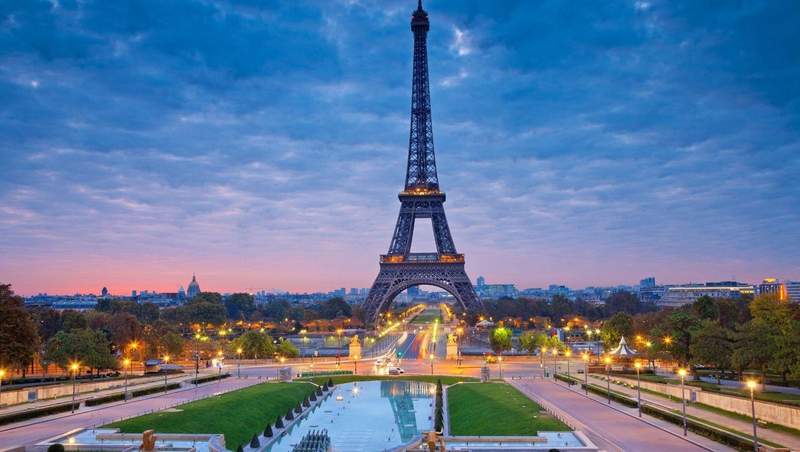 Vue emblématique de la tour Eiffel à Paris au coucher du soleil avec les jardins du Trocadéro au premier plan.