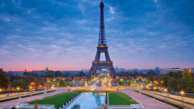 Vue emblématique de la tour Eiffel à Paris au coucher du soleil avec les jardins du Trocadéro au premier plan.
