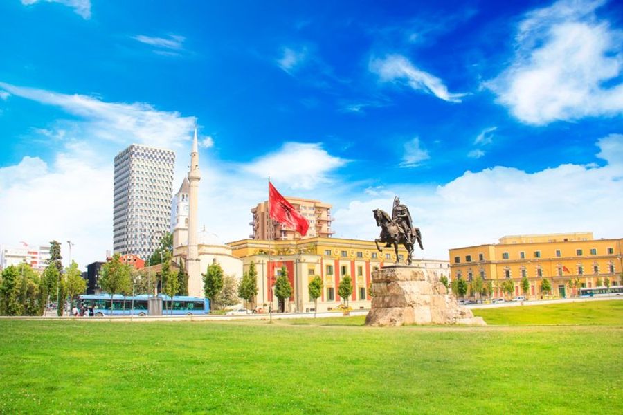 Place Skanderbeg à Tirana avec la statue de Skanderbeg et des bâtiments historiques.