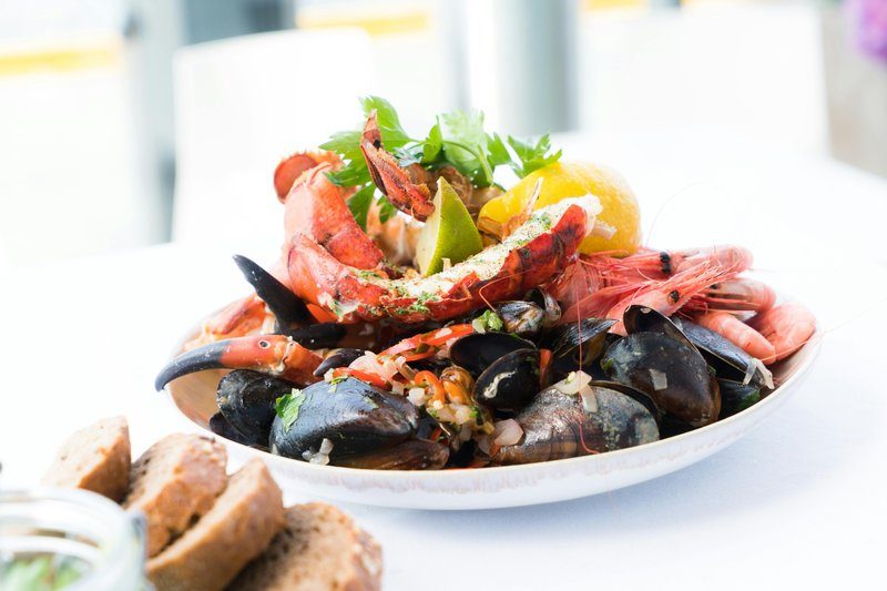 Assiette de fruits de mer variés, avec du homard, des moules, des crevettes et du citron, idéale pour un repas à Monopoli, Italie.