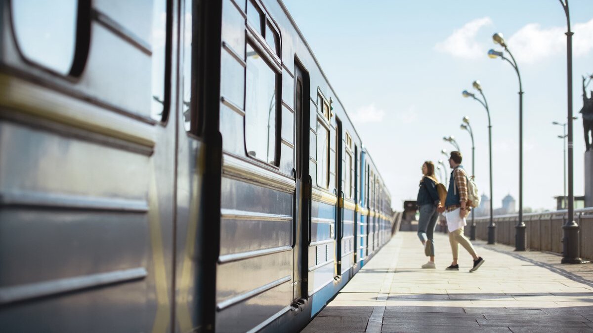 Jeune couple marchant main dans la main le long d’un quai de gare à côté d’un train bleu
