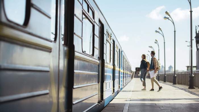 Jeune couple marchant main dans la main le long d’un quai de gare à côté d’un train bleu