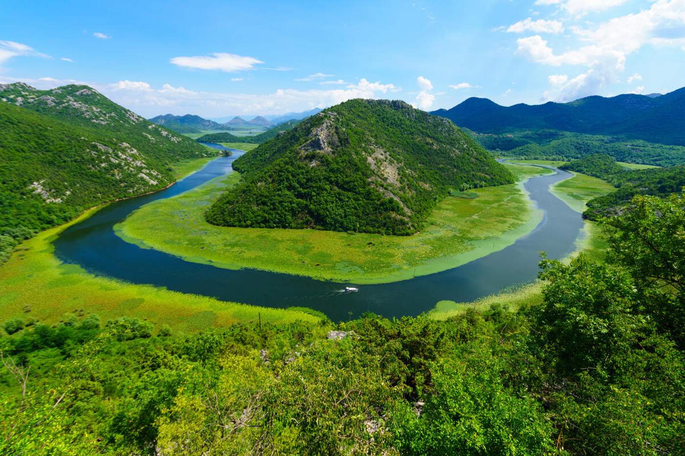 Vue en hauteur sur les méandres de la rivière Crnojevića encerclant une colline boisée dans le parc national du lac de SKadar, Monténégro