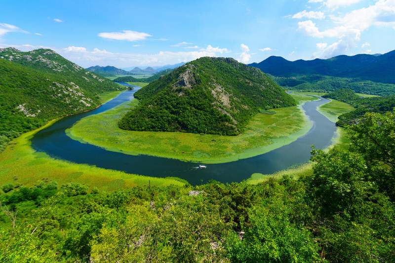 Vue en hauteur sur les méandres de la rivière Crnojevića encerclant une colline boisée dans le parc national du lac de SKadar, Monténégro