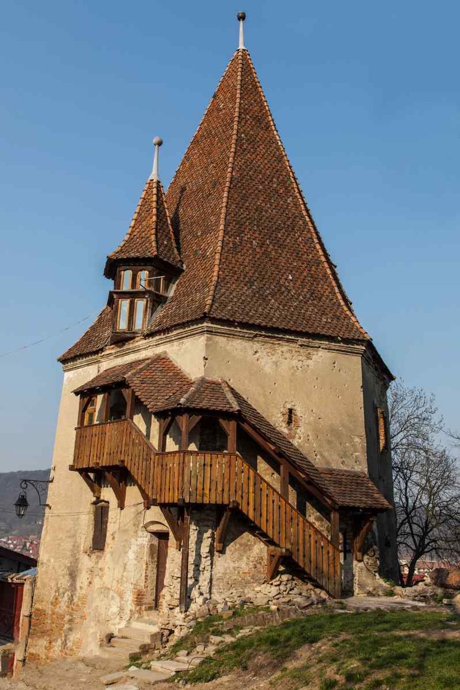 Tour médiévale en pierre avec un toit en tuiles rouges.