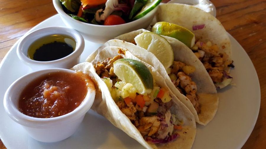 Assiette de tacos garnis de lime, accompagnés de sauces et d’une salade fraîche, typiques de la cuisine de Tamarindo au Costa Rica.
