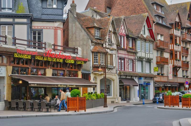 Façades à colombages colorées et terrasse de restaurant à Deauville, typiques de l’architecture normande.